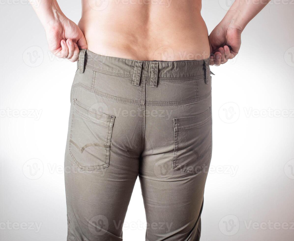 A fat man with overweight and fat folds on his stomach wears small green shorts on a white background. Obesity and malnutrition concept, diet photo