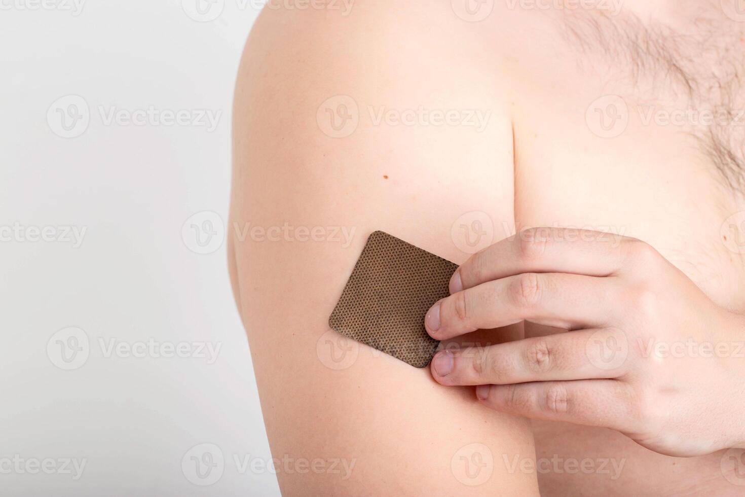 The guy with the anti-tobacco medical plaster on the skin of the body to get rid of the bad habit of smoking, a dose of nicotine photo
