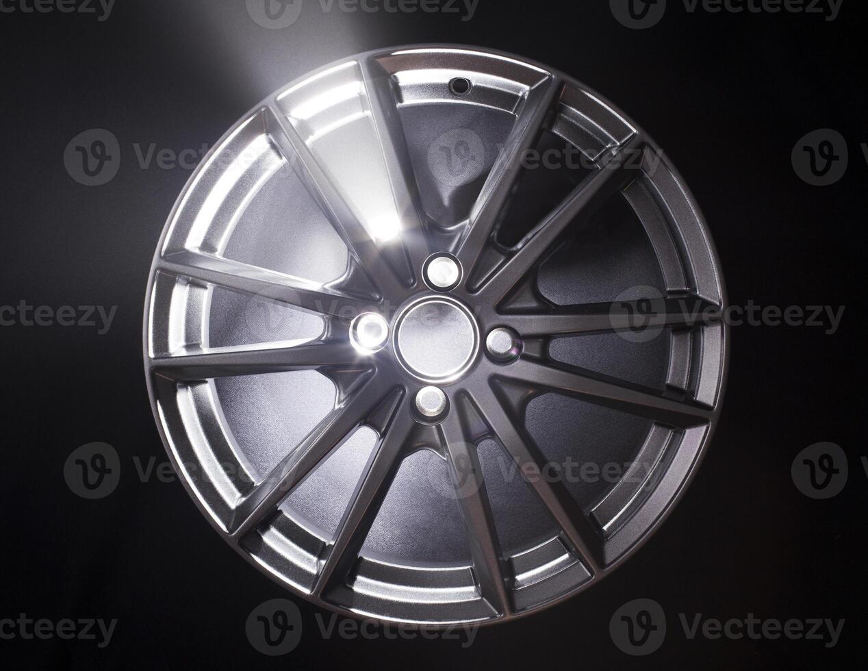 Modern beautiful car alloy wheel in the form of rays that is highlighted by rays of light and sparkle, black background photo