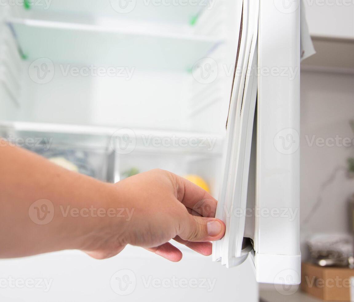 Replacing the torn sealing rubber on the refrigerator door with a new rubber. photo