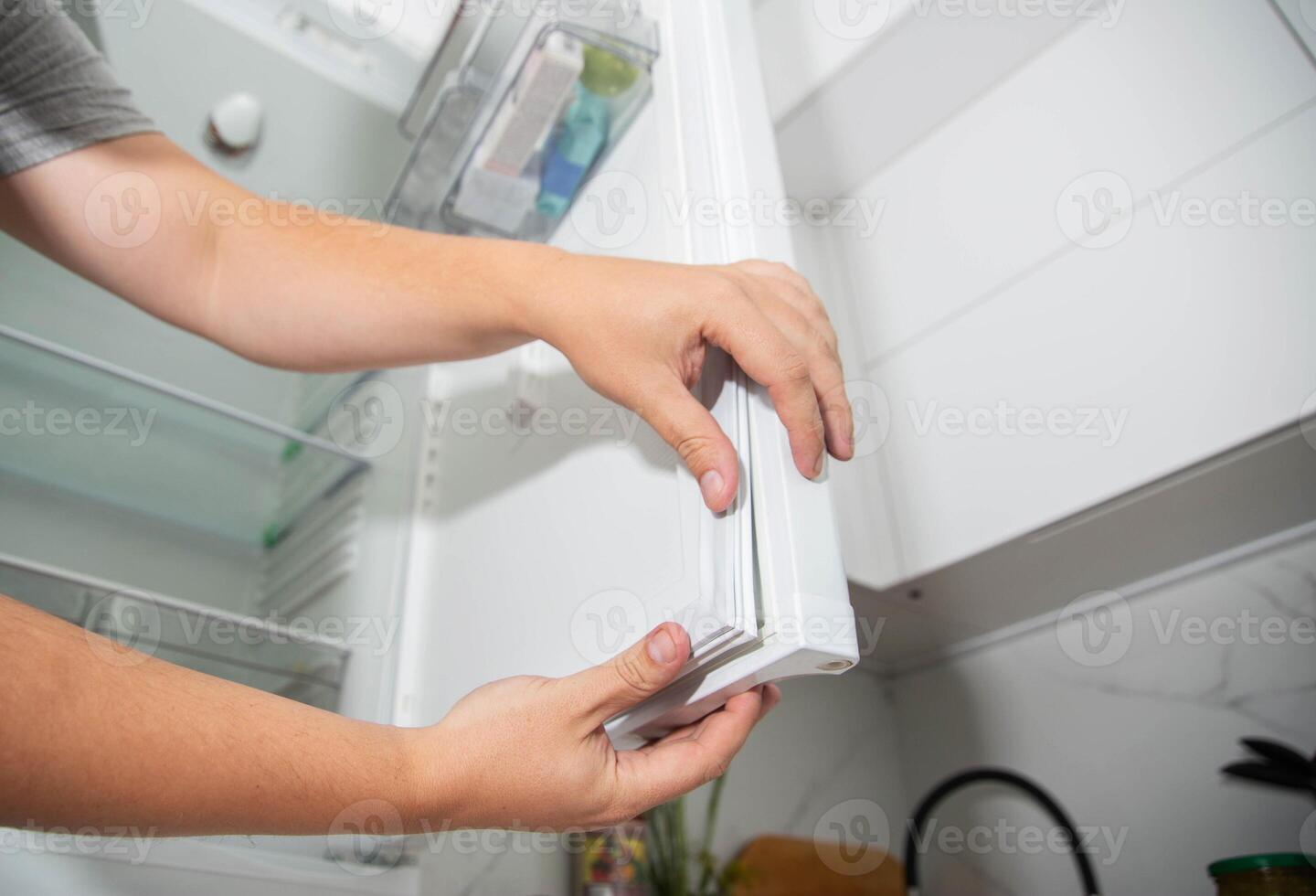 Replacing the torn sealing rubber on the refrigerator door with a new rubber. photo
