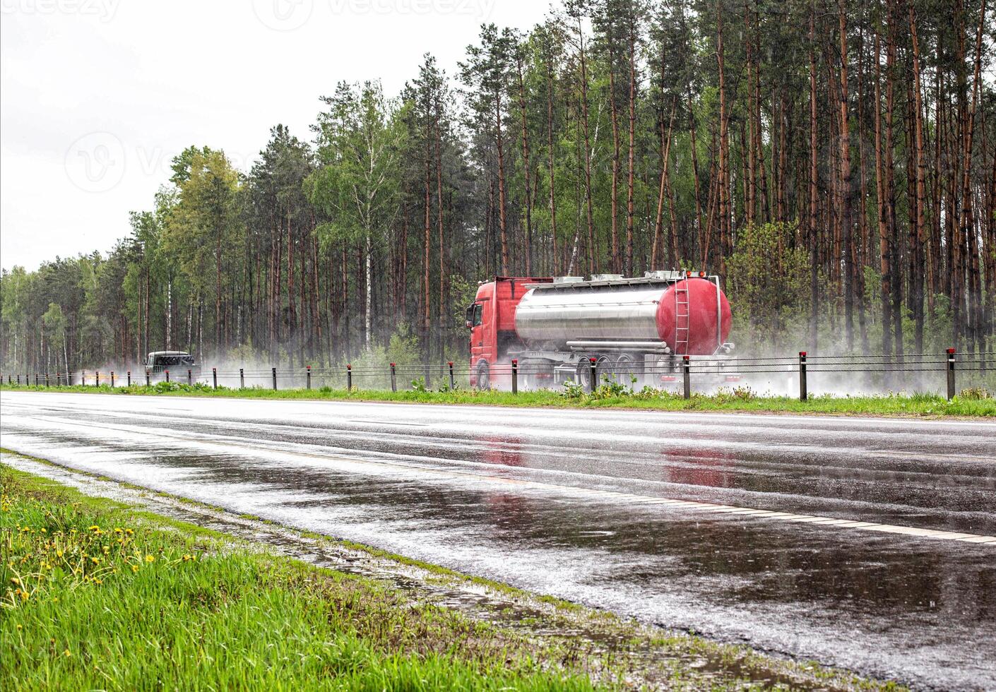 A truck with a semi-trailer tanker transports a dangerous cargo of fuel on a motorway slippery in the rain, industry photo