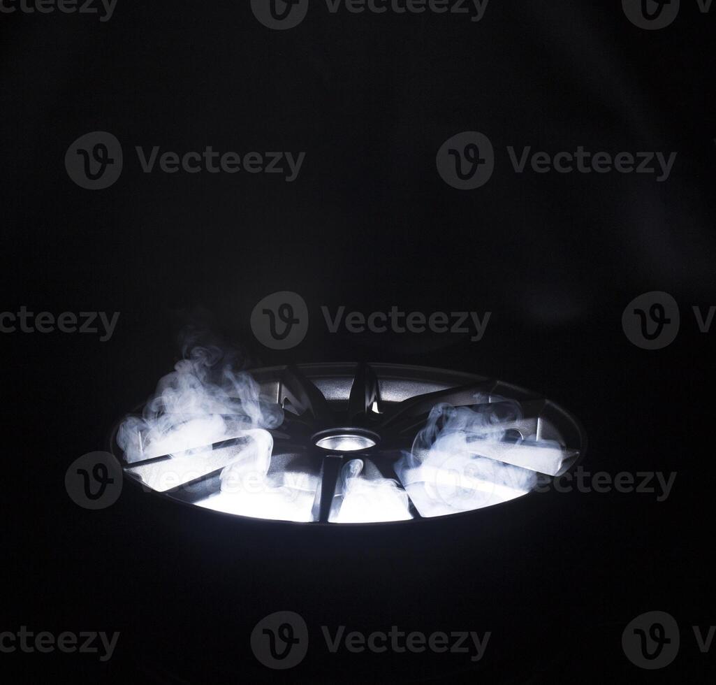A modern beautiful automotive alloy wheel in the form of rays that is highlighted by rays of light and brilliance. Stylish cast smoke, industry photo