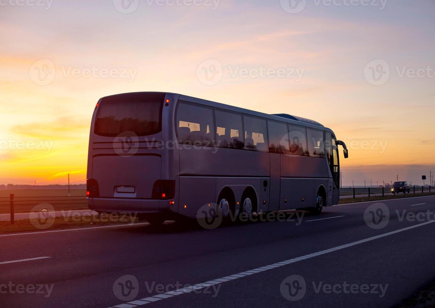 A large comfortable passenger bus against the orange sky with sunset rides on the highway. The concept of European passenger transportation in companies, e-ticket photo