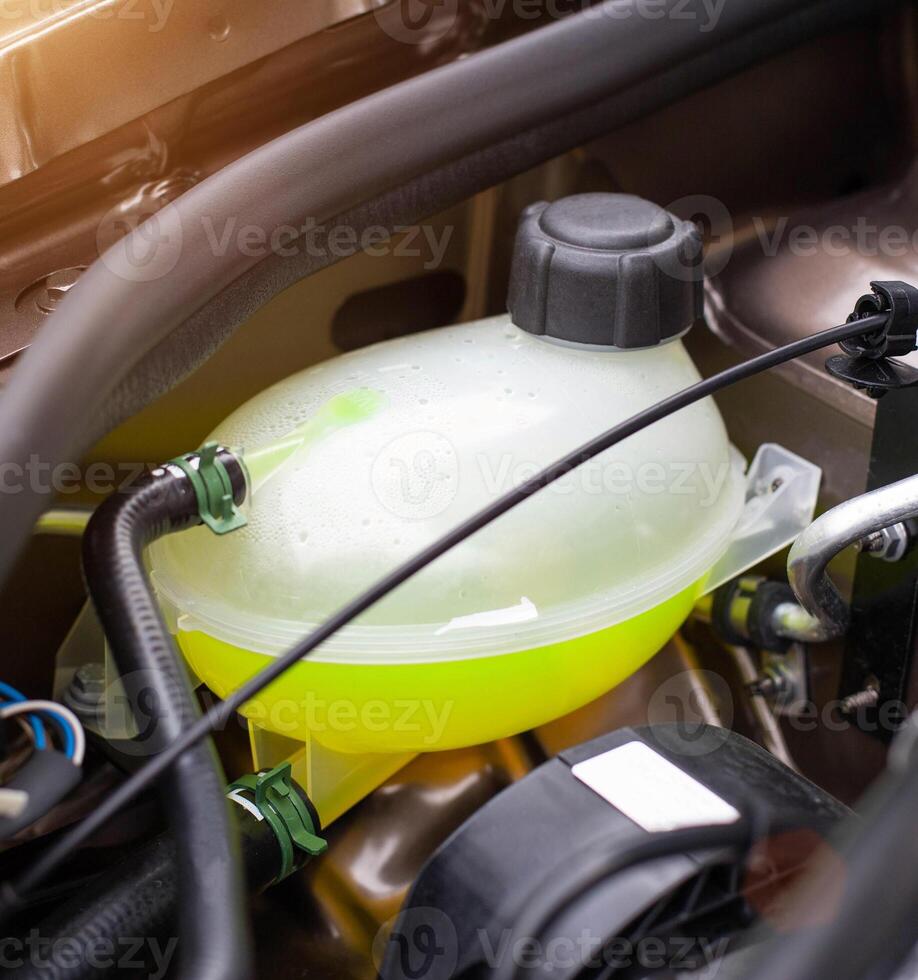 Car reservoir for filling coolant. Yellow antifreeze in the expansion tank, freezing temperature concept in winter. photo