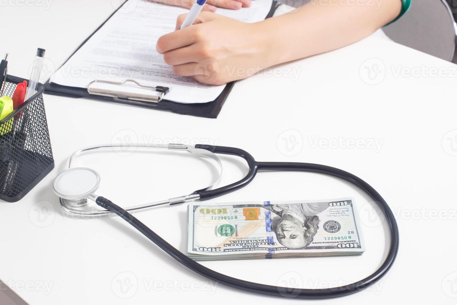 A stethoscope and money dollars lie on a white medical table at the doctor's. Concept of bribery in medicine and sale of clandestine drugs, copy space photo