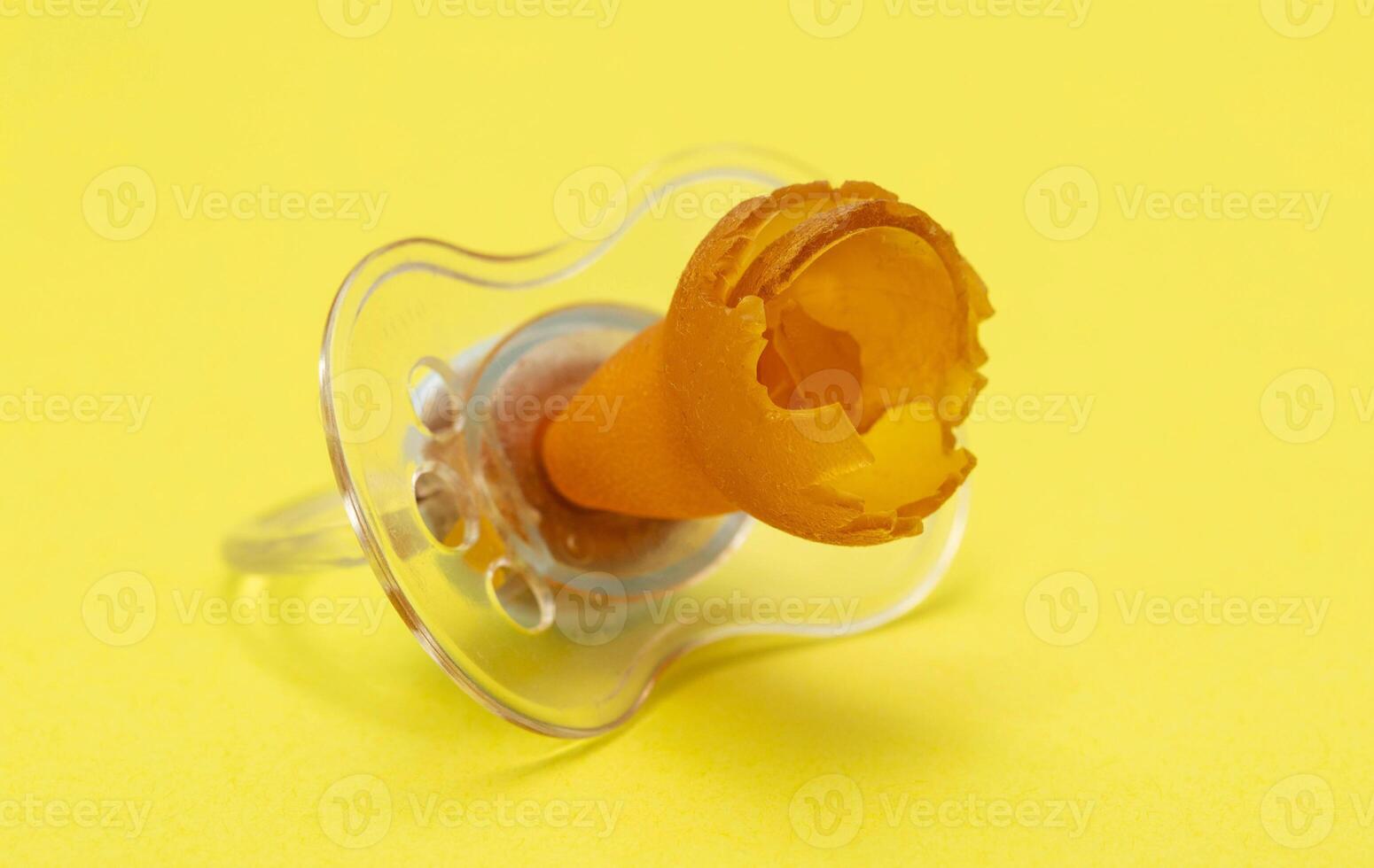 A chewed baby pacifier on a yellow background. Concept of teething in children, close-up. photo