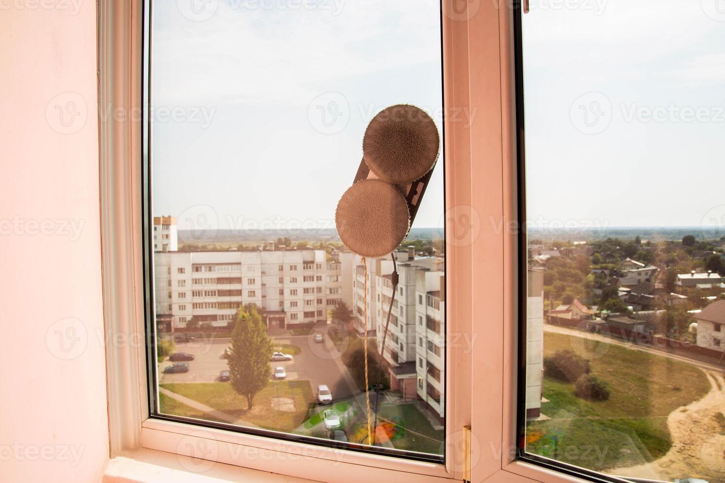 A modern vacuum robot window cleaner washes glass from dirt and stains on a pvc balcony frame. Fall safety. Copy space for text photo