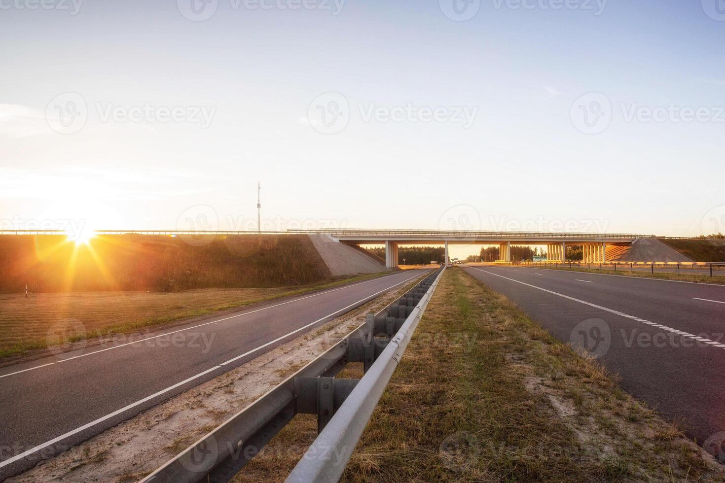 The highway is crossed by a bridge with a road against the backdrop of a sunny sunset. Engineering and architecture concept, copy space for text photo
