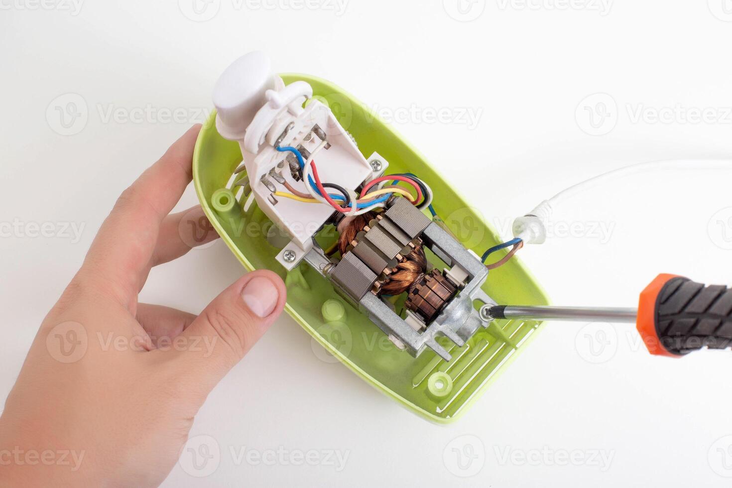 The hands of a male household appliance repairman unscrew the parts of a hand mixer with a screwdriver. Household appliance repair service concept, close-up photo