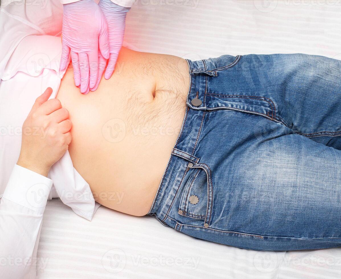 The doctor probes the epigastric region on the abdomen of a patient with pain and inflammation. Stomach and duodenal diseases concept photo