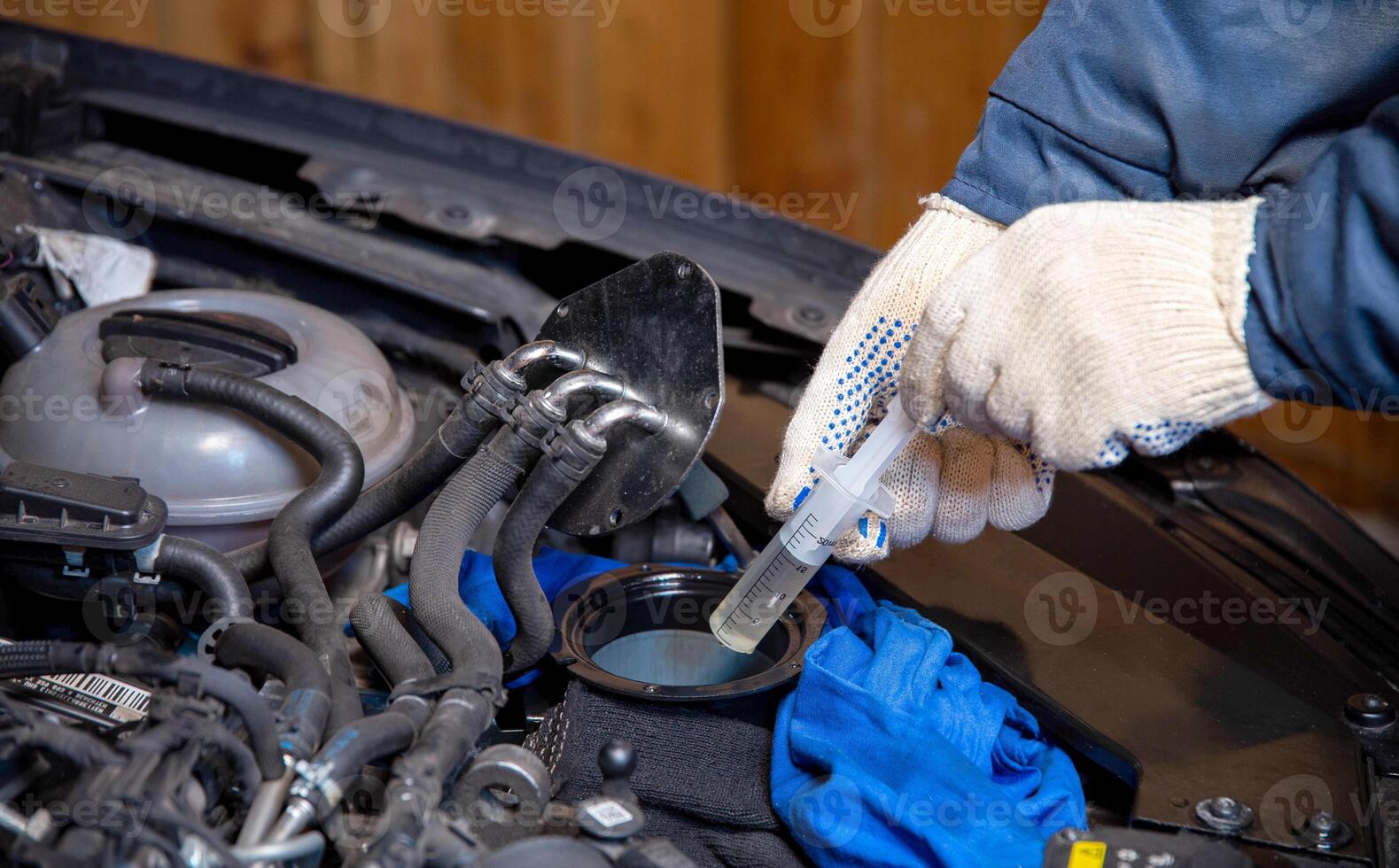 The mechanic sucks old fuel out of the fuel filter with a syringe. Replacing the crowd filter and cleaning the fuel system. Close-up photo