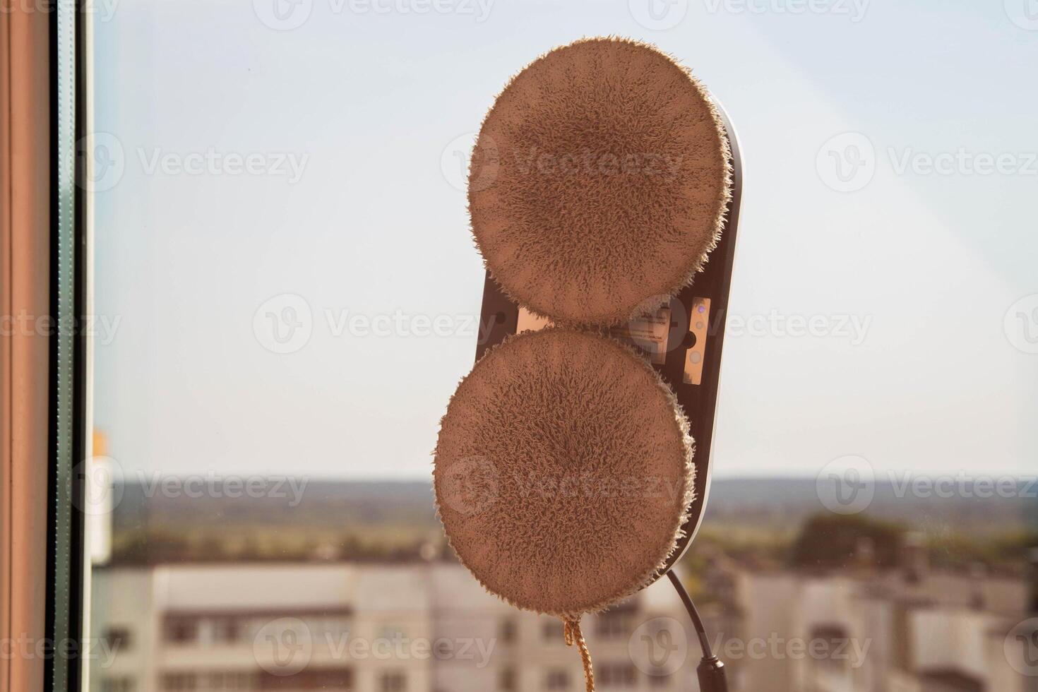 A modern vacuum robot window cleaner washes glass from dirt and stains on a pvc balcony frame. Fall safety. Copy space for text photo