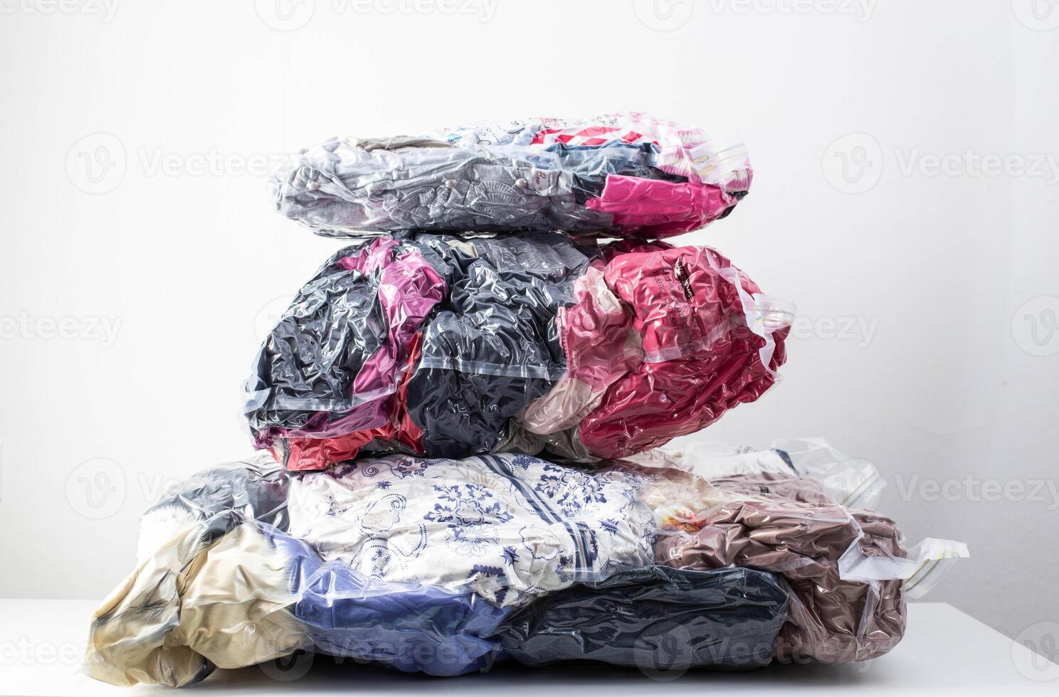 Multi-colored clothes and things packed in vacuum bags for storage on a white background. Modern compact storage technology, close-up photo