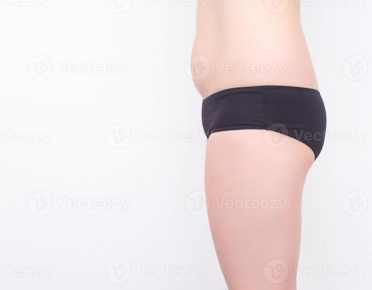 Girl in black shorts with small buttocks on a white background. The concept of buttock augmentation with the help of implants, white background, copy space, healthy photo