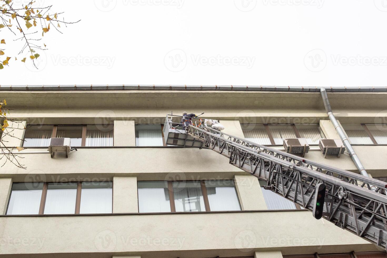 Girl worker washes windows at a height in the house, washer photo