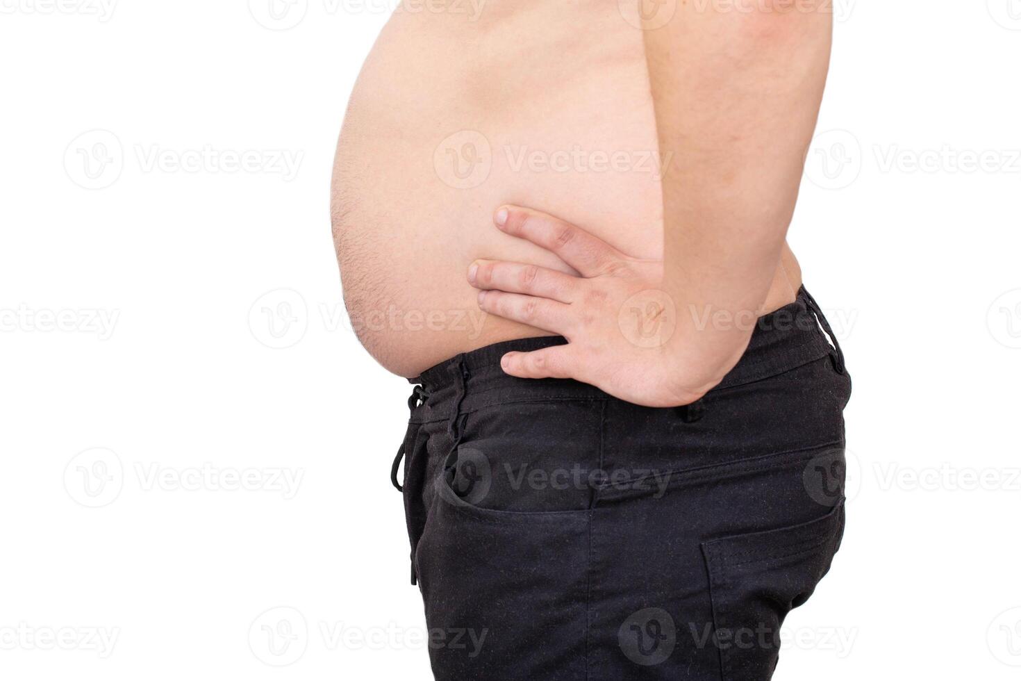 A man with a big belly in black pants on a white background, isolate. Obesity and malnutrition concept, close-up photo