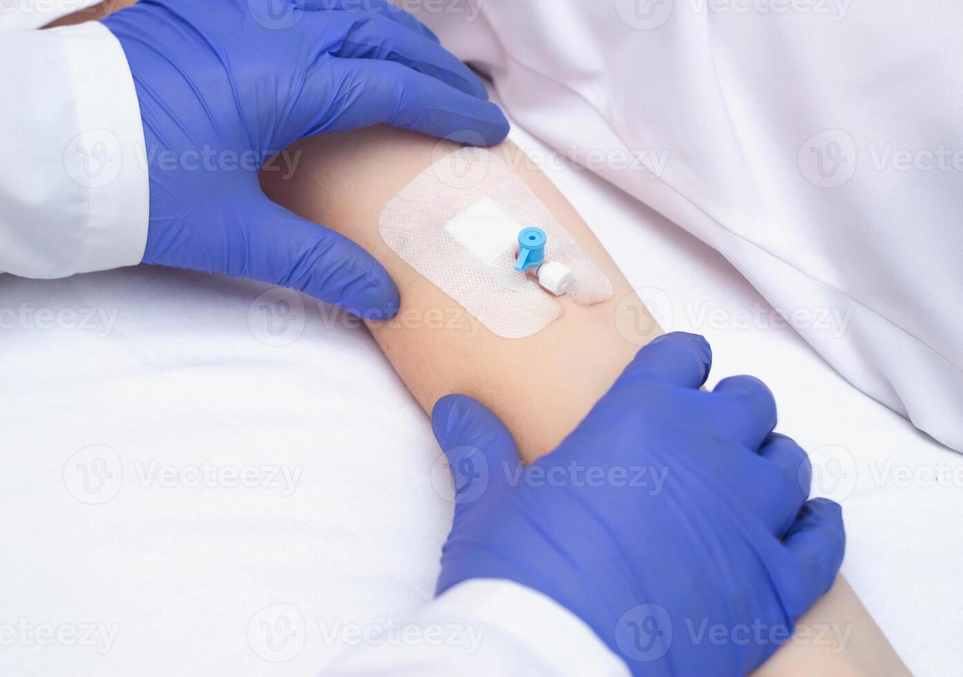 A doctor in medical gloves holds the patient's hand with an intravenous catheter. Concept of human blood diseases, leukemia, copy space for text photo