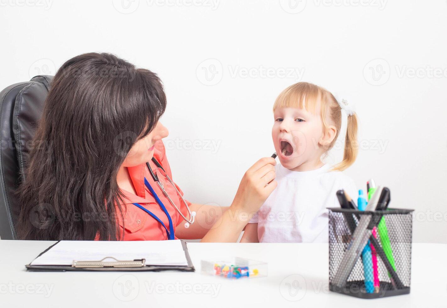 Woman doctor pediatrician examines the red throat of a little girl. Sore throat in children, concept for the treatment of adenoids and infections, copy space photo
