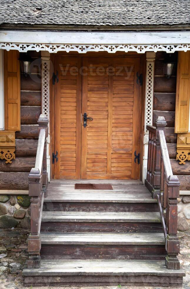 Wooden porch with steps and a door to a log cabin. Village houses architecture, close-up photo