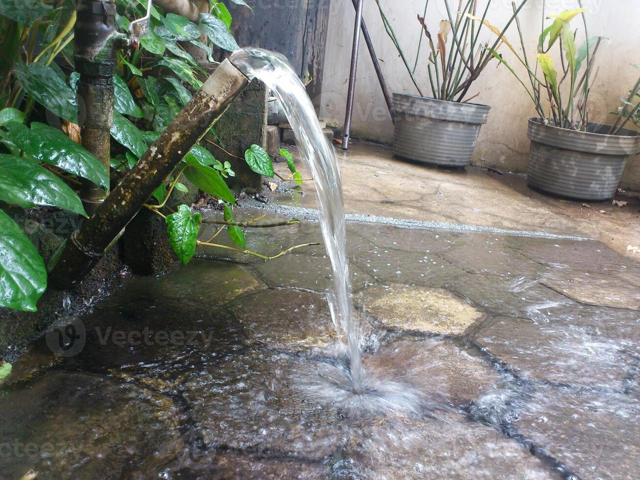 A water fountain is pouring water into a potted plant photo