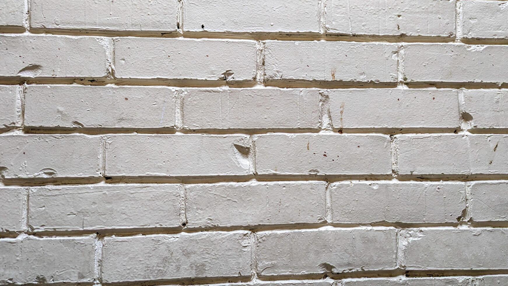 A weathered white brick wall displaying subtle textures and uneven surfaces, likely found in an urban setting, creating a rustic backdrop suitable for various design projects photo