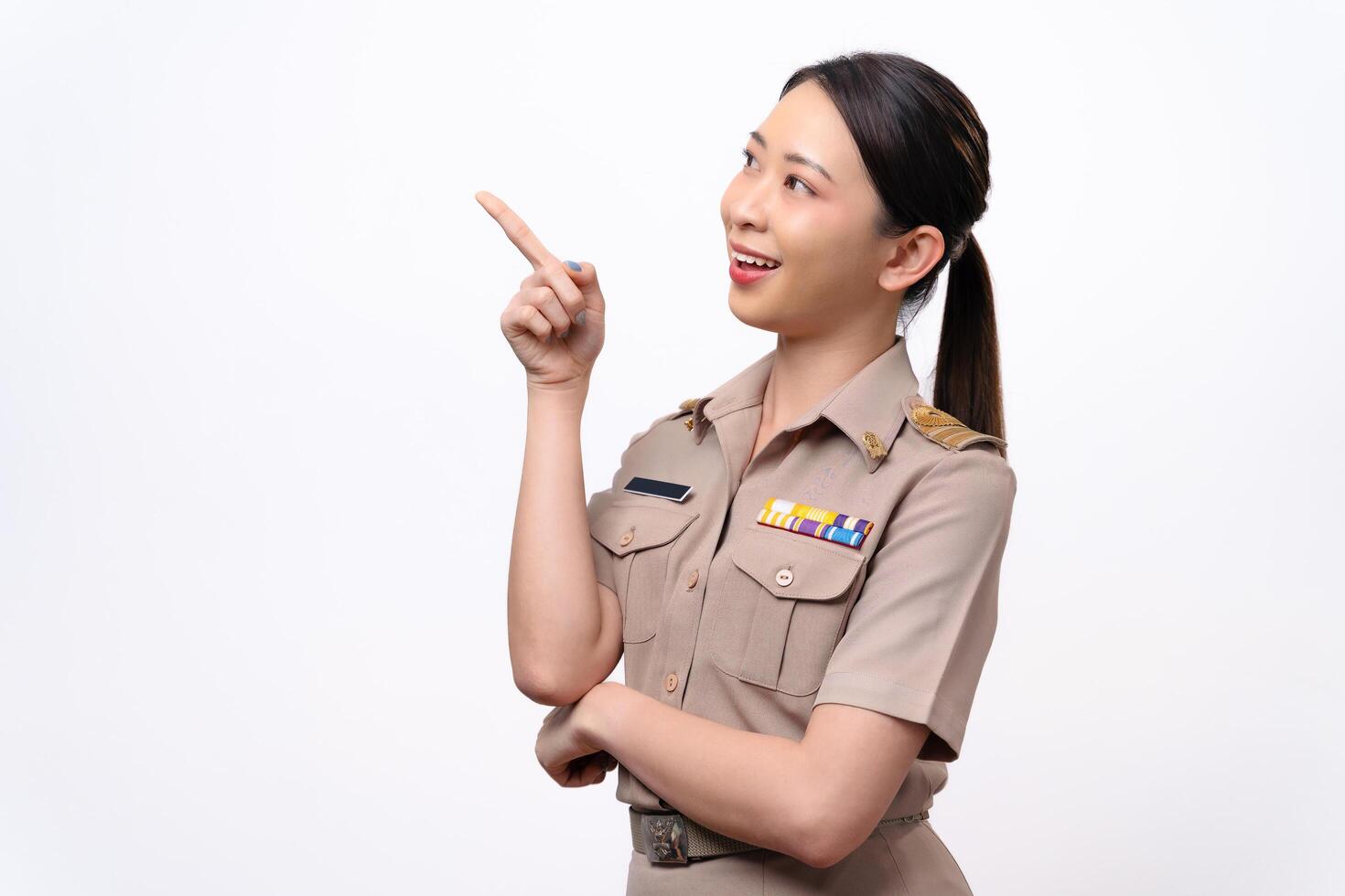 A woman in a Thai asian teacher uniform is pointing to the empty space with a smile on her face. photo