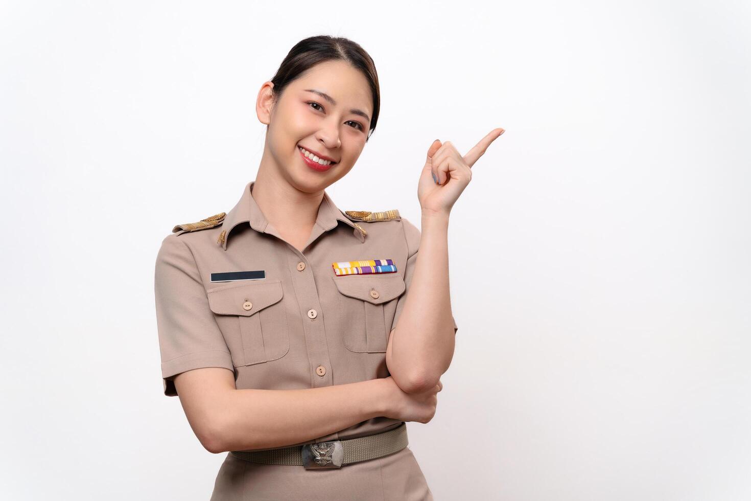 A woman in a Thai asian teacher uniform is pointing to the empty space with a smile on her face. photo
