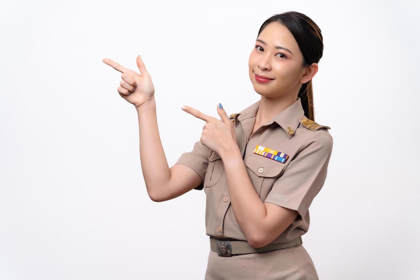 A woman in a Thai asian teacher uniform is pointing to the empty space with a smile on her face. photo