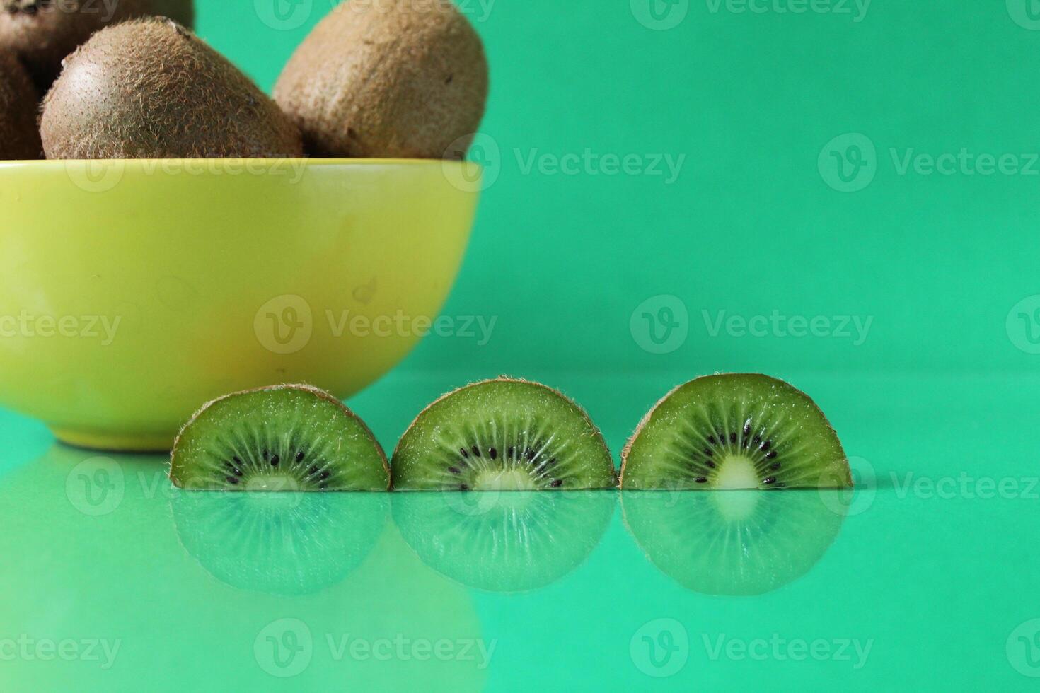 still life kiwi fruit in a yellow bowl plate and next to a kiwi copyspace slice photo