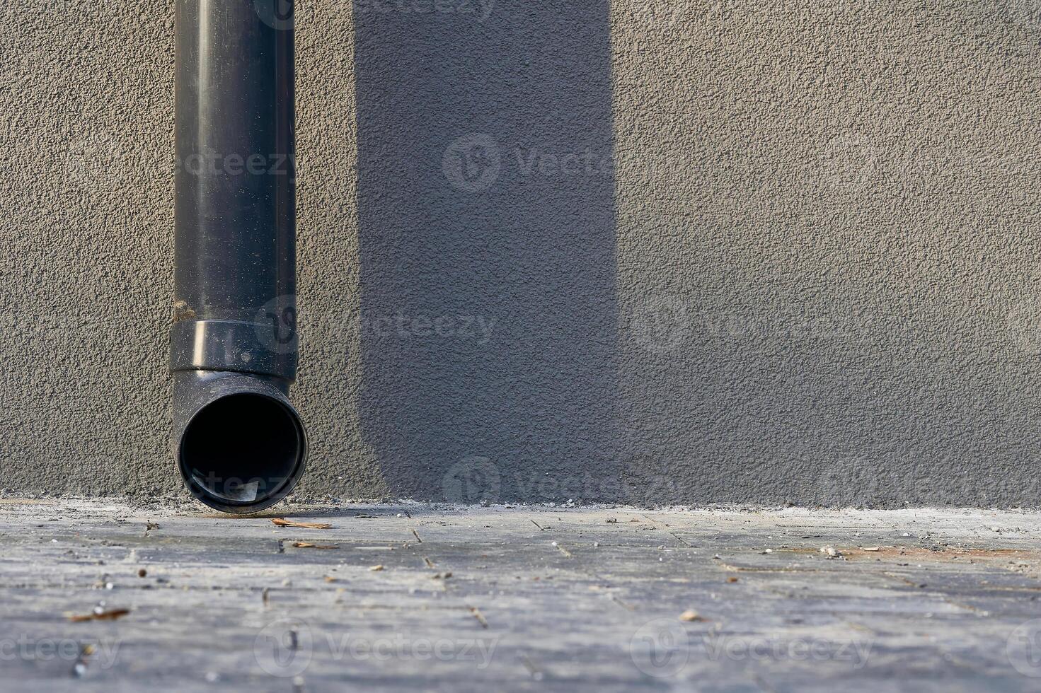 Rain runoff.New plastic drain pipe on a gray plastered wall photo
