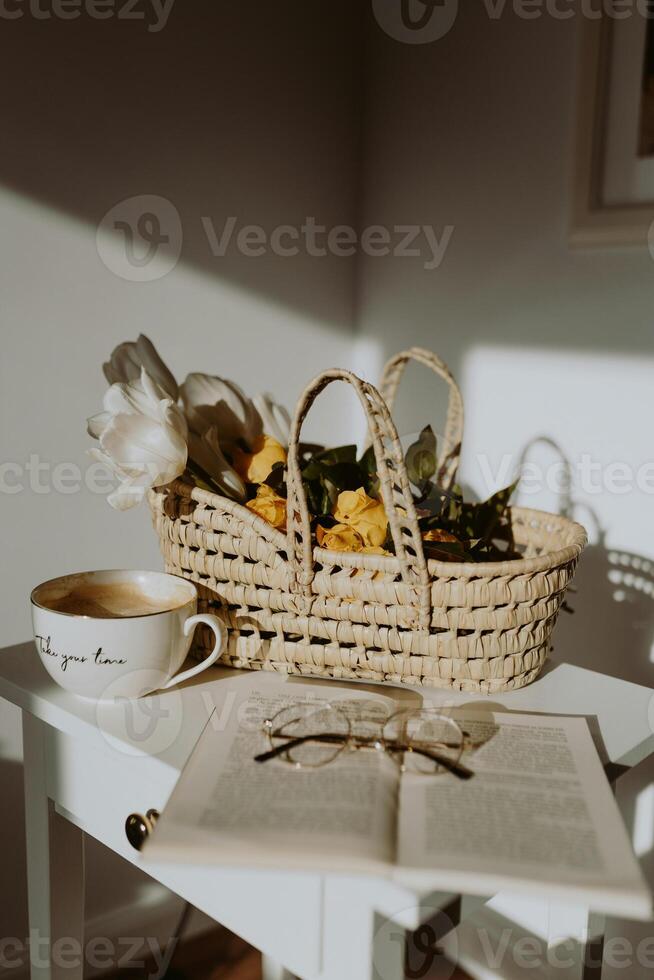 a basket of flowers and a book on a table photo