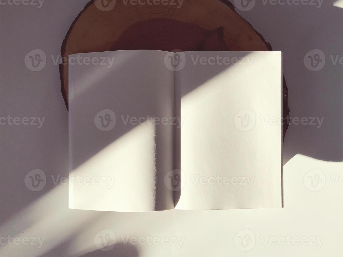 an open book on a wooden table with the sun shining on it photo