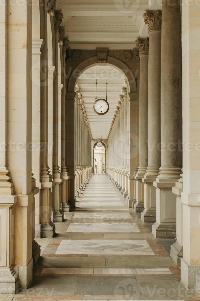 a long hallway with columns and a clock on the wall photo