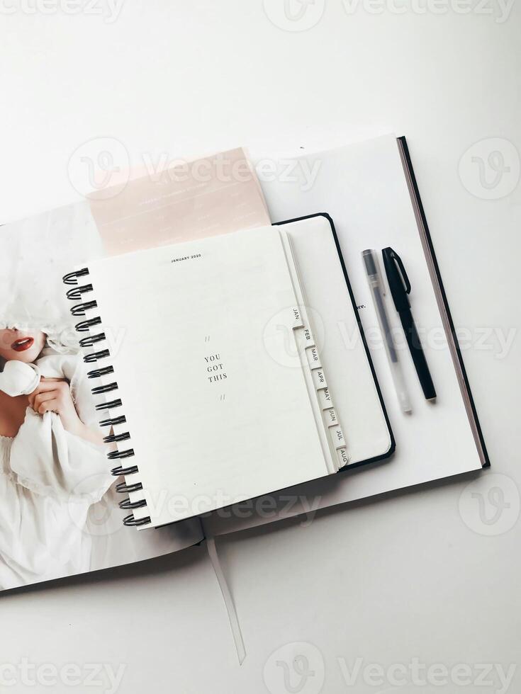 a planner notebook and pen on a white surface photo