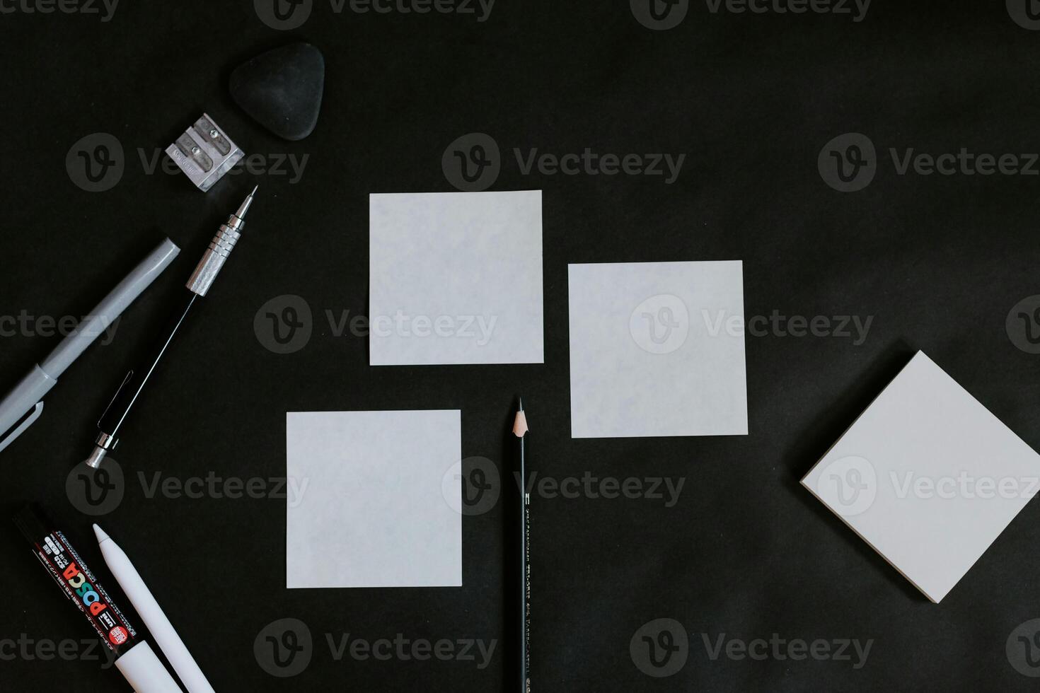 a black surface with a white square a pen a pencil and a paperclip photo