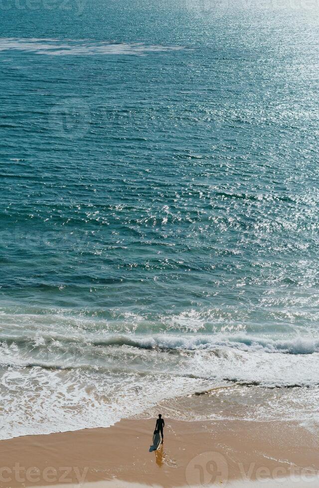 a person walking on the beach with a surfboard photo