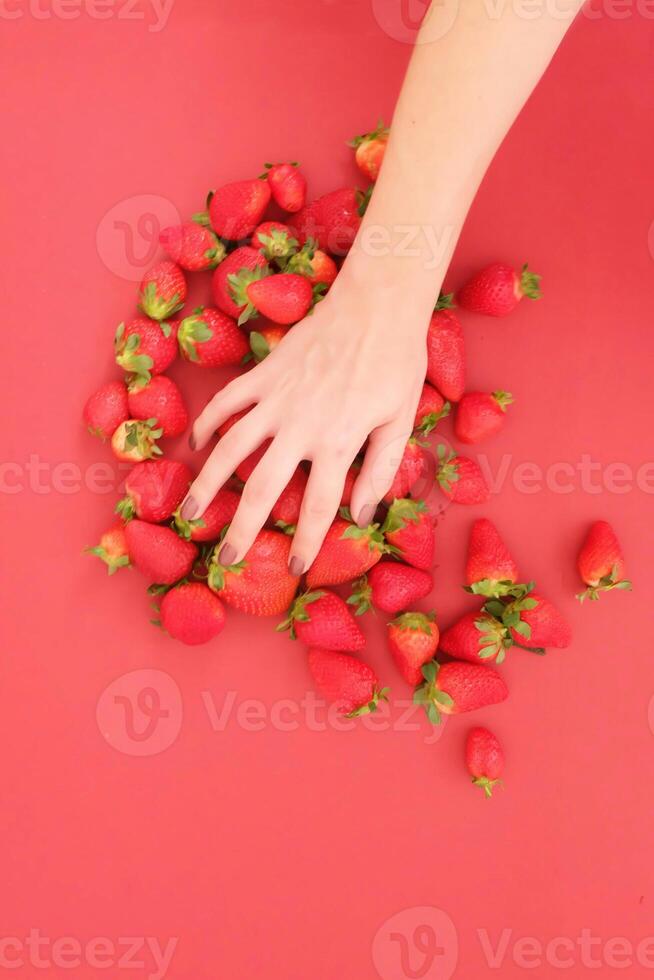a person reaching for strawberries on a red surface photo
