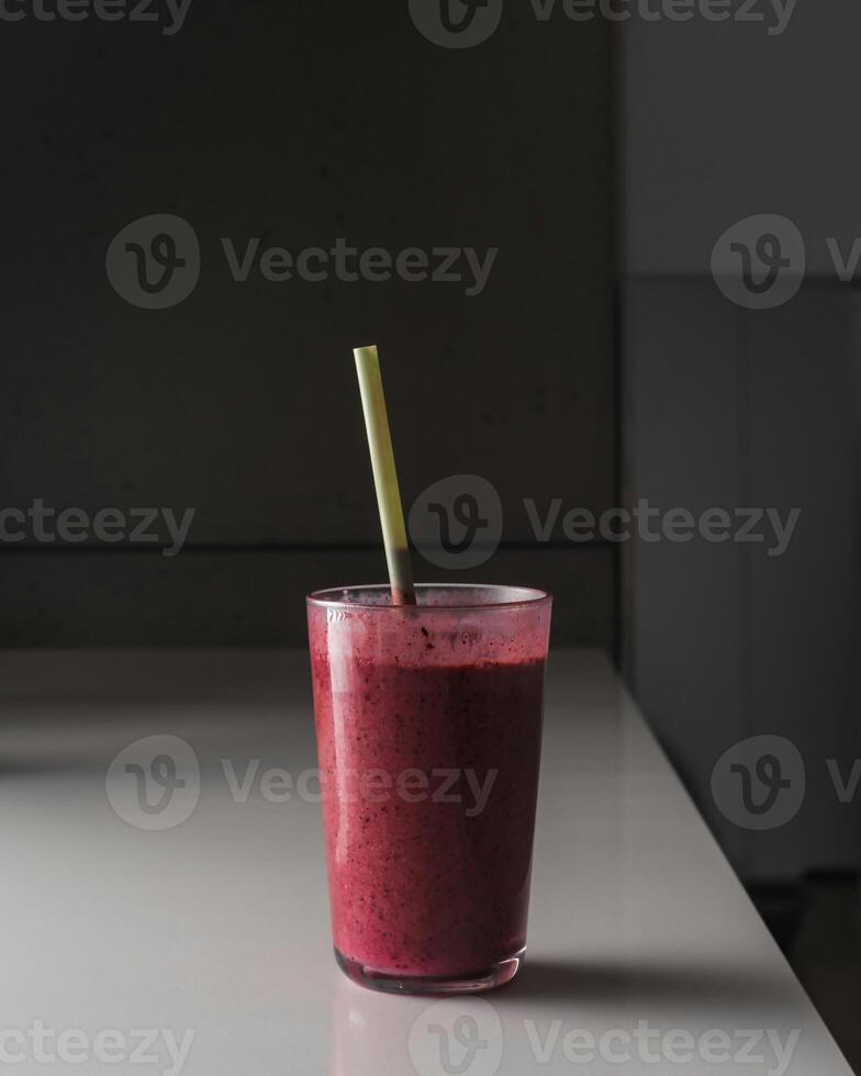 a smoothie with a straw sitting on a counter photo