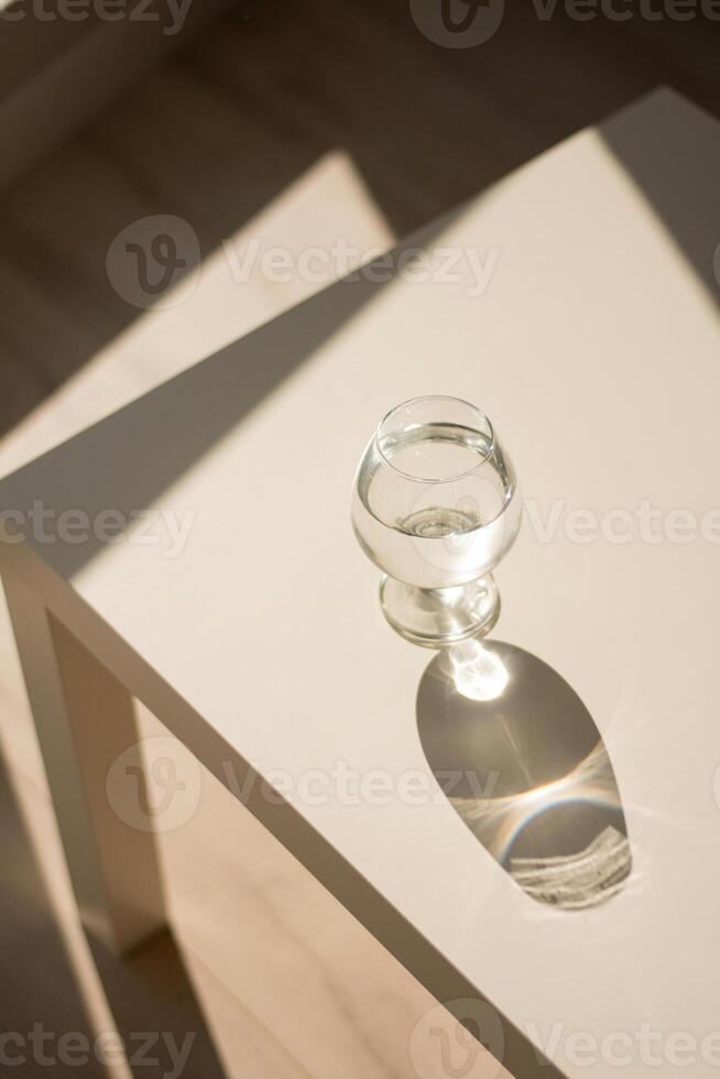 a white table with a glass of water on it photo