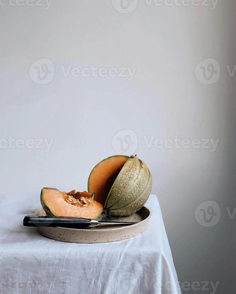 a melon on a plate with a knife on top photo