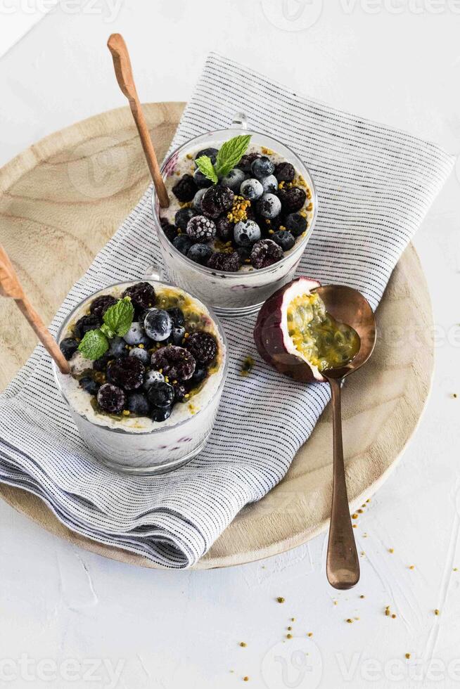 two bowls of blueberry yogurt with spoons on a plate photo