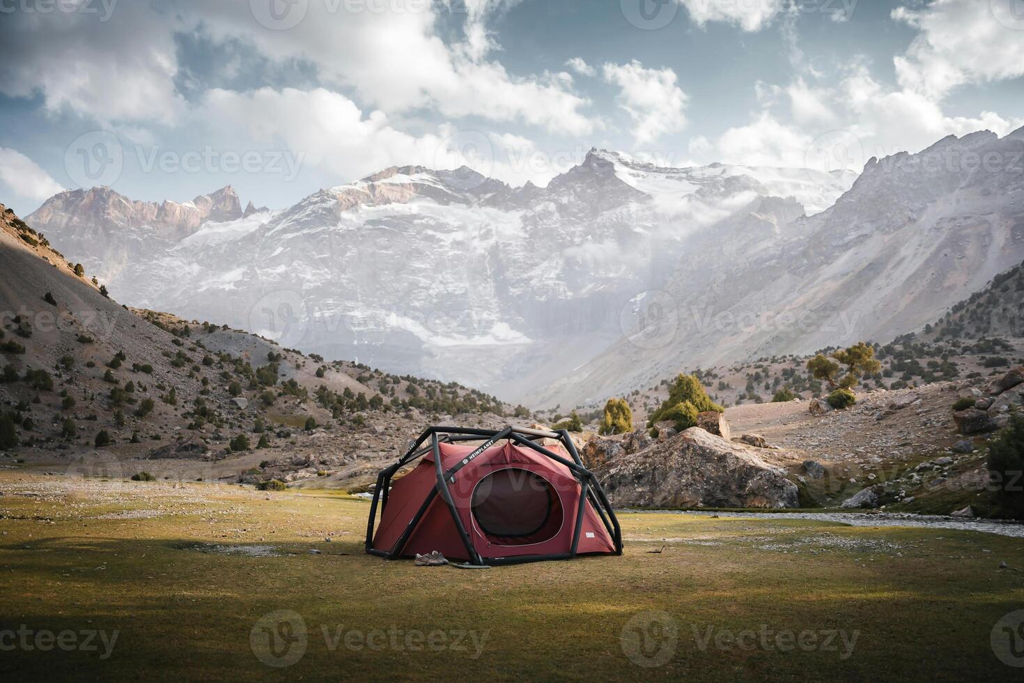 a tent is set up in a field with mountains in the background photo