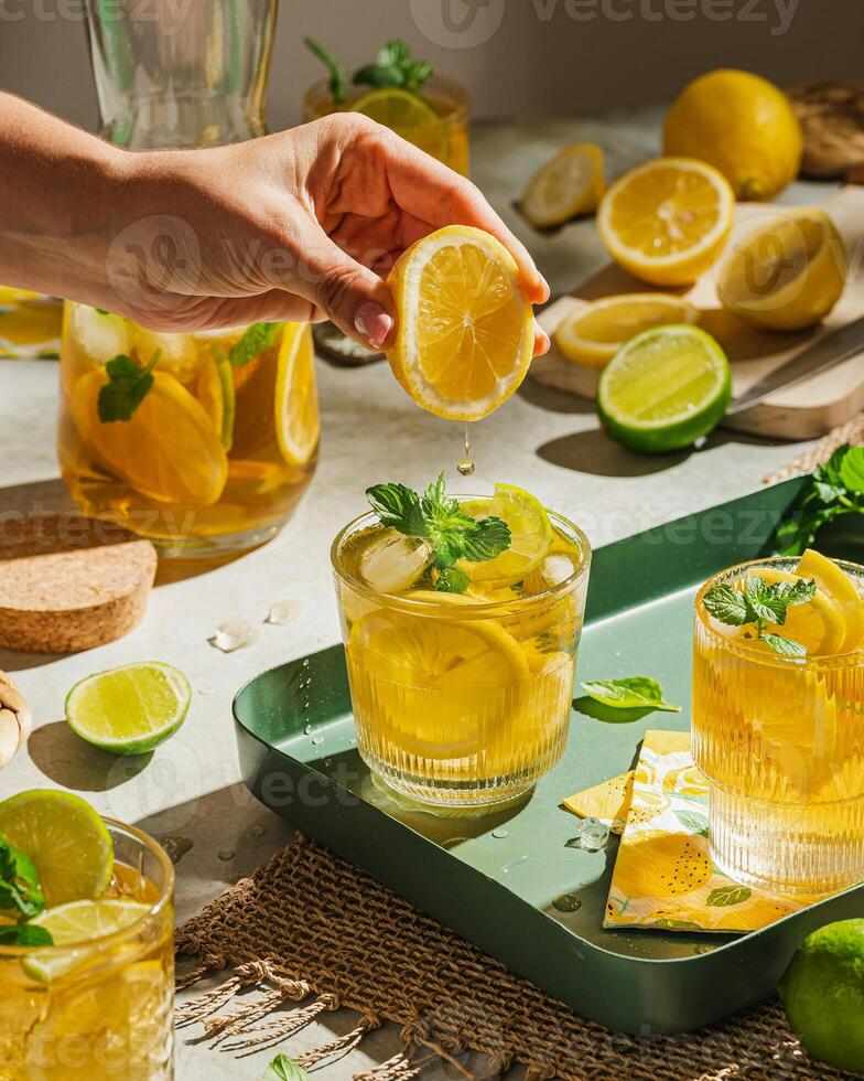 a person is holding a lemon slice over a glass of lemonade photo