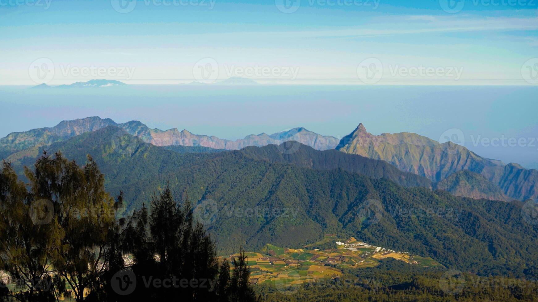 Experience the breathtaking sunset atop Mount Arjuno, where the sun casts a golden glow over the landscape. The sky transforms into a stunning blend of blue and vibrant hues photo