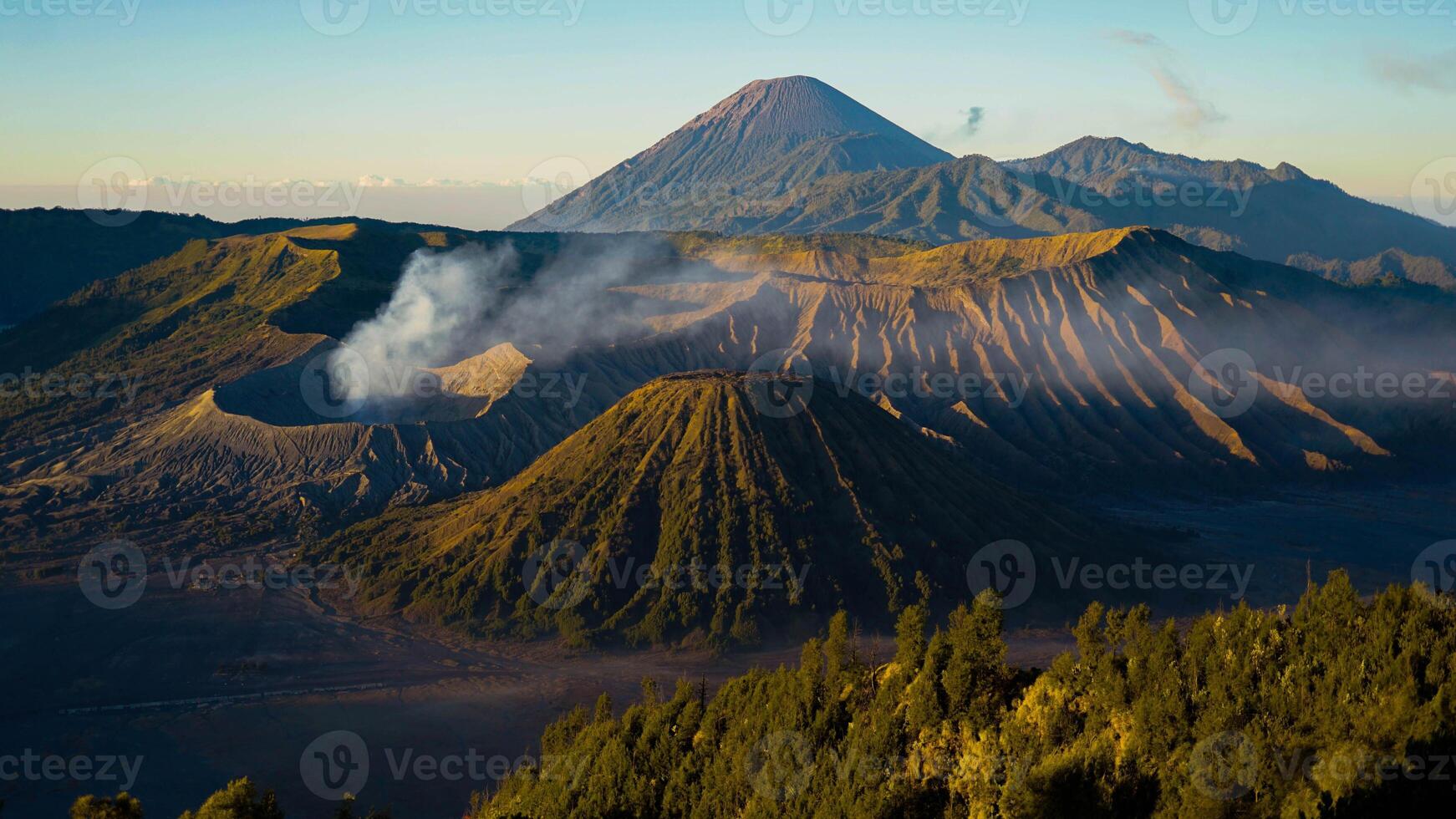 A stunning sunrise at Mount Bromo reveals a vibrant sunset, with clouds gracefully enveloping the peak, showcasing East Java's natural beauty. photo