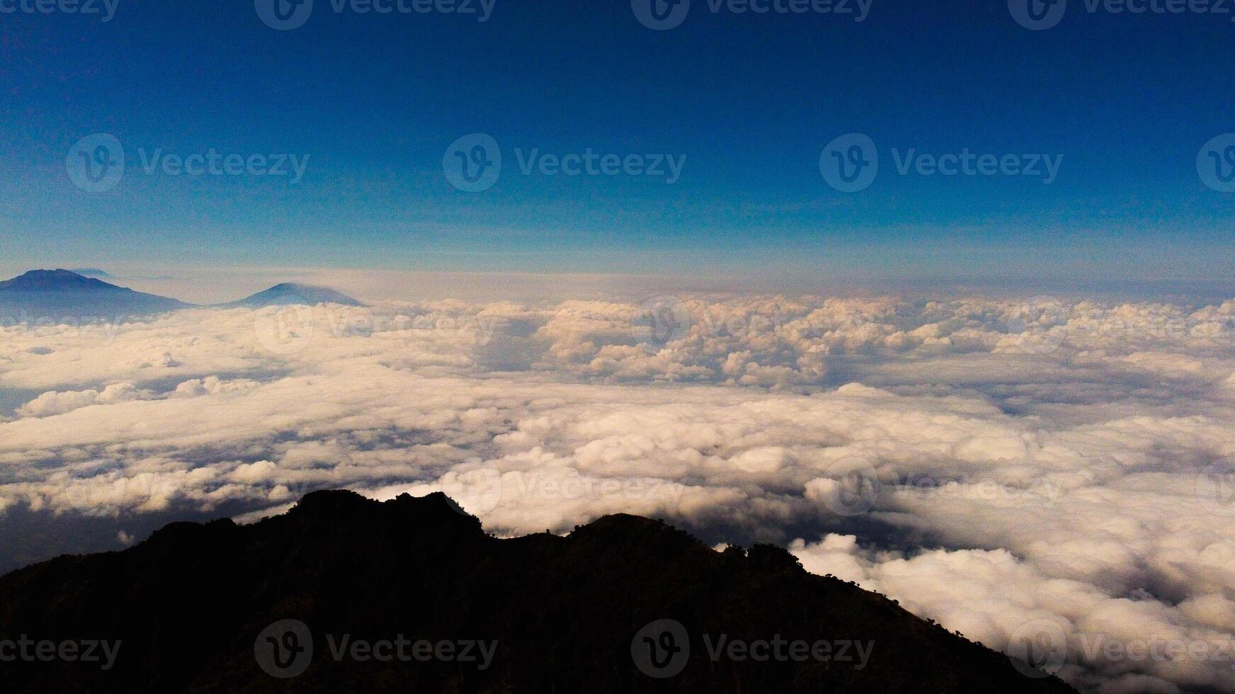 From the summit of Mount Prau, breathtaking views of three towering peaks unfold. A favorite among hikers, this stunning landscape showcases Indonesia's natural beauty and adventure. photo