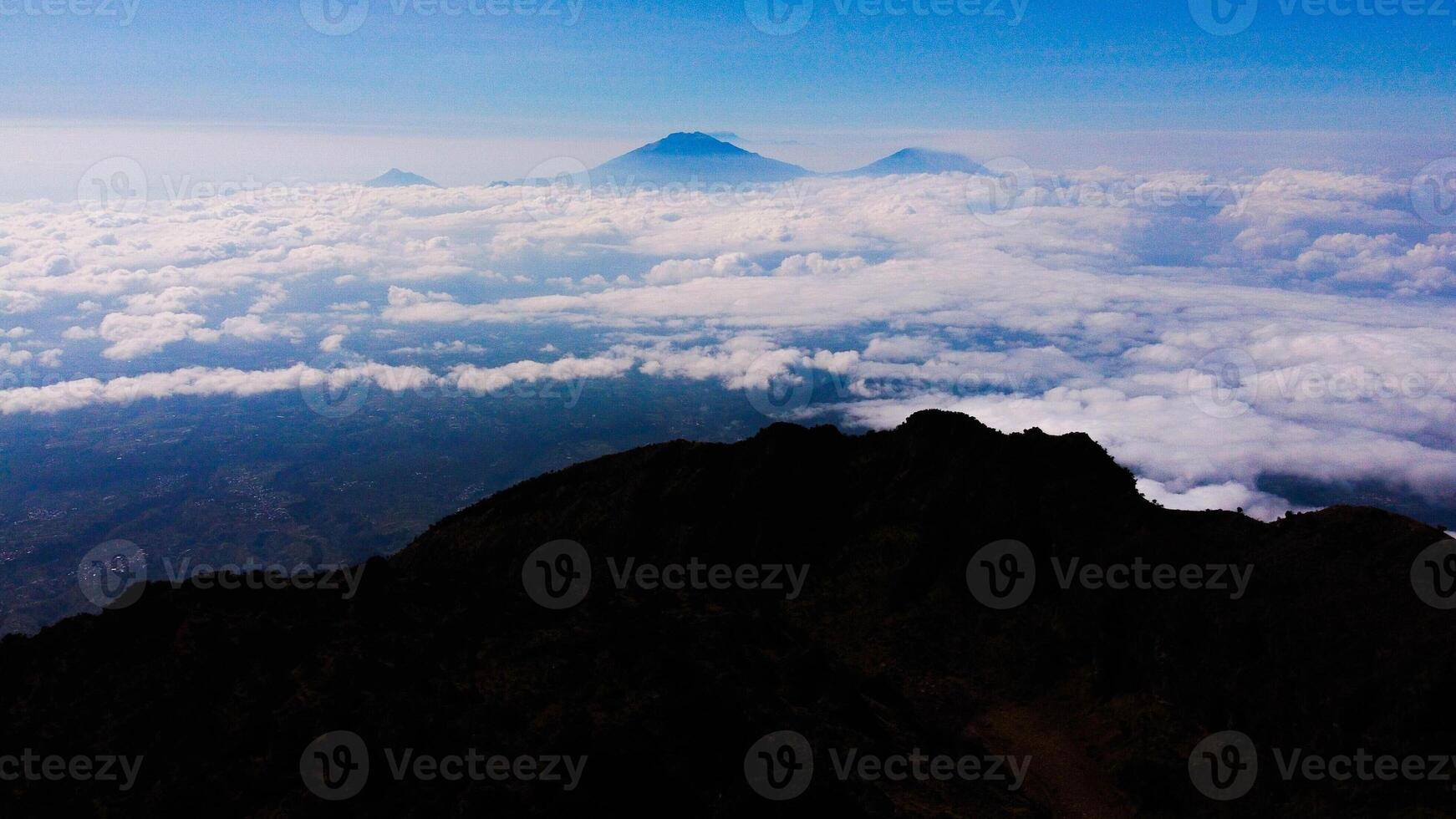From the summit of Mount Prau, breathtaking views of three towering peaks unfold. A favorite among hikers, this stunning landscape showcases Indonesia's natural beauty and adventure. photo