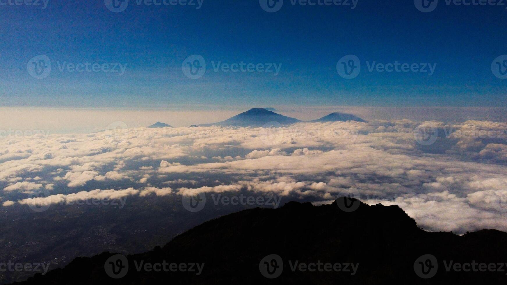 From the summit of Mount Prau, breathtaking views of three towering peaks unfold. A favorite among hikers, this stunning landscape showcases Indonesia's natural beauty and adventure. photo