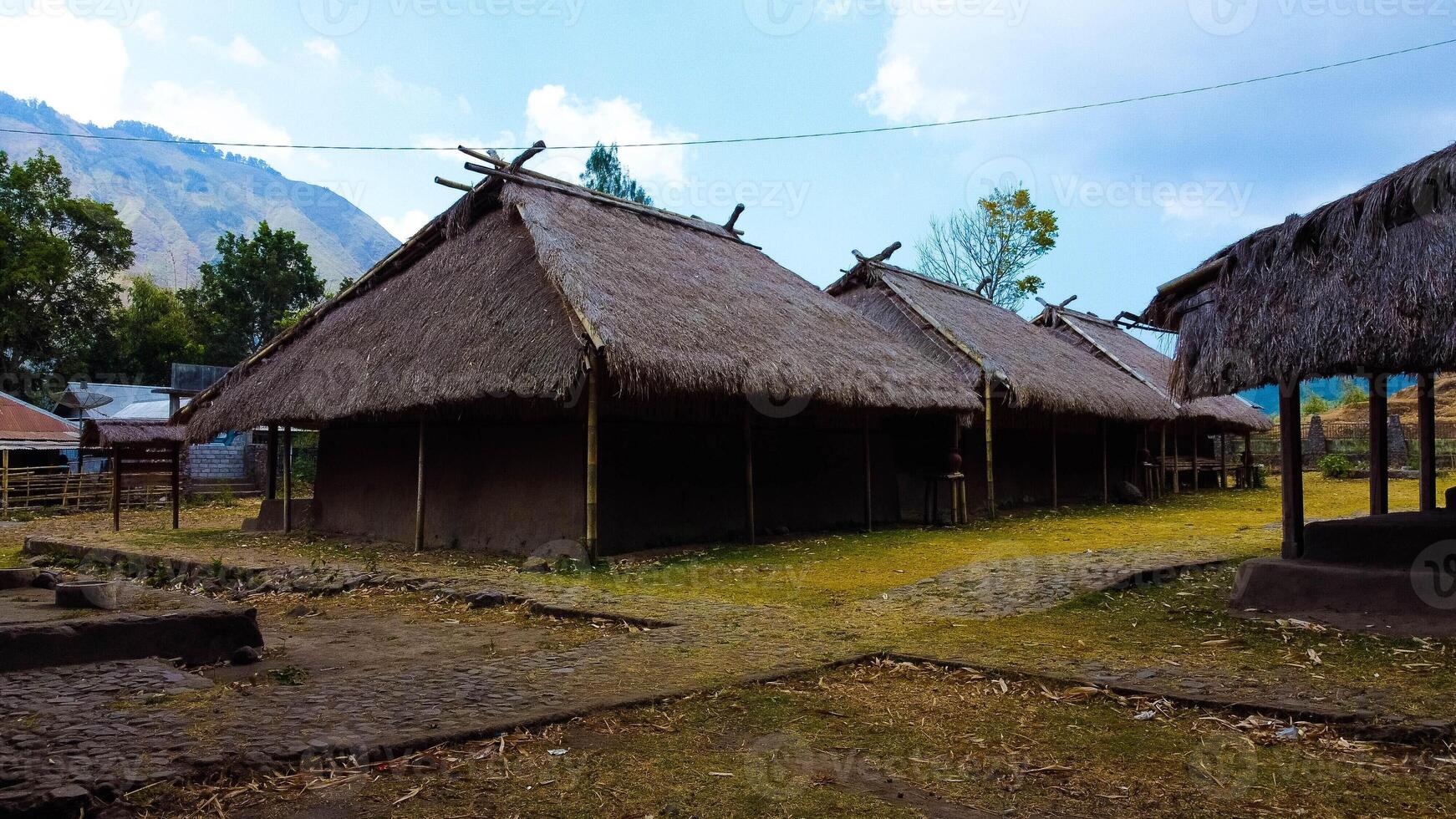 Discover aerial views of the traditional village at the foot of Mount Rinjani, showcasing a cool atmosphere, lush gardens, and beautiful hills surrounding the area. photo